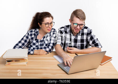 Nerds, geek, bespectacled and funny people concept - funny student couple in glasses sitting at the table. Stock Photo