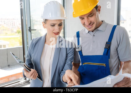 Construction worker and architect looking at plan on site Stock Photo