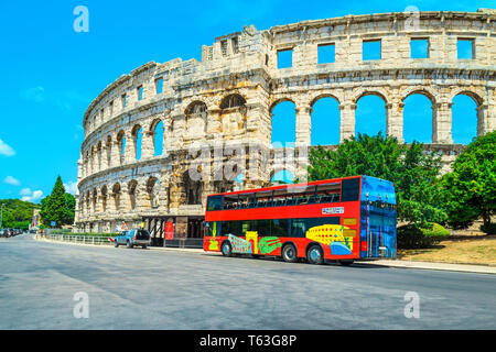 Spectacular old historical building with colorful touristic bus. Street view with famous ancient Roman amphitheatre (Arena) in Pula town, Istria penin Stock Photo