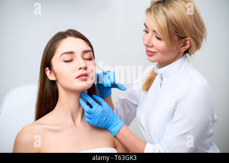 Beautician doctor with botulinum toxin syringe making injection to to remove crow's feet. Cheek volume enhance mesotherapy. Anti-aging treatment and f Stock Photo