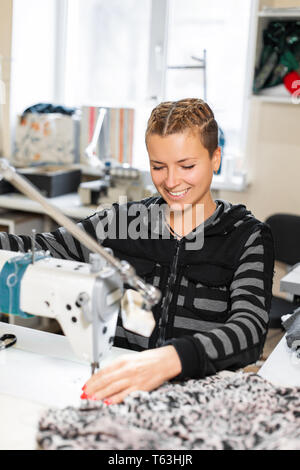 Seamstress sewing at machine, portrait. Female tailor stitching material at workplace. Preparing fabric for clothes making. Tailoring, garment Stock Photo