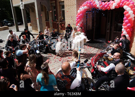 06/08/2008Moscow, Russia.  The groom carries the bride in his arms .Bikers sitting bikes and meet a couple leaving the registrar Stock Photo