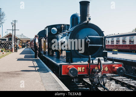 Sheringham, UK - April 21, 2019: Conductor standing by the cab of The Poppy Line train, also known as the North Norfolk Railway, a Heritage Steam Rail Stock Photo