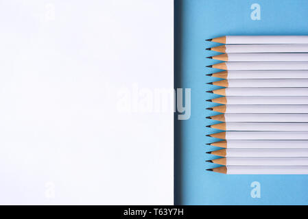 Pencils and a notebook on blue surface. Close up. Copy space for text Stock Photo