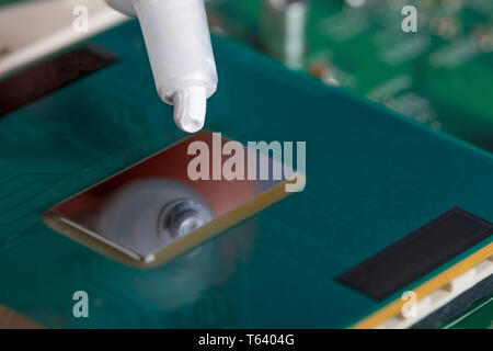 A tube of thermal grease over the processor chip. Computer assembly stage. Part of laptop Stock Photo