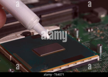 A tube of thermal grease over the processor chip. Computer assembly stage. Part of laptop Stock Photo