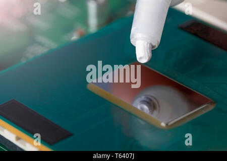 A tube of thermal grease over the processor chip. Computer assembly stage. Part of laptop Stock Photo