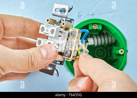 Worker is mounting light switch inside gypsum plasterboard, electrical maintenance. Stock Photo