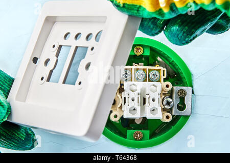 Putting a top on the new european standard push button inside gypsum plasterboard wall by electrician. Stock Photo