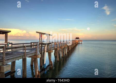 Early moonset and sunrise over the Naples Pier on the Gulf Coast of Naples, Florida in summer. Stock Photo