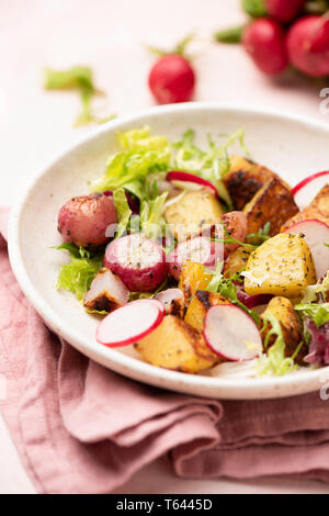 Healthy spring salad with potato, radish and green leaf salad on plate. Roasted vegetables salad. Closeup view, selective focus Stock Photo