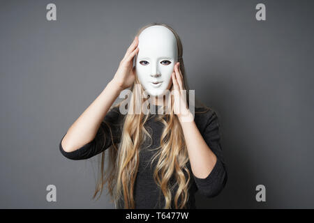 mysterious young woman adjusting her mask with her hands Stock Photo