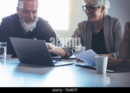 Mature business woman explaining business plan to colleagues. Mature manager planning new strategy with colleagues in meeting. Stock Photo