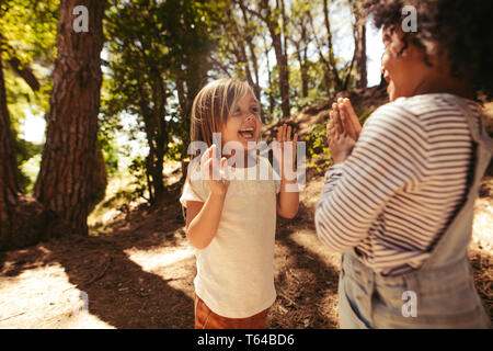 Cheerful girls playing clapping games in forest. Cute children playing games in a park. Stock Photo