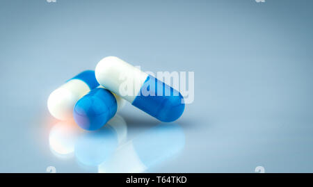 Blue and white capsule pills on gradient background. Global healthcare concept. Antibiotics drug resistance. Antimicrobial capsule pills. Pharmaceutic Stock Photo