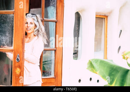 Silver society adult people caucasian woman with long white hair looking outside home from open door - alternative diversity people concept - portrait Stock Photo