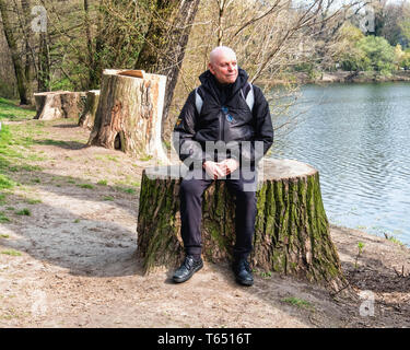 Berlin,Pankow. Weissensee State park, White Lake public park with Elderly senior man sitting on tree stump Stock Photo