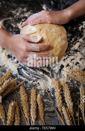 Knead the dough with the ingredients on dark background Stock Photo