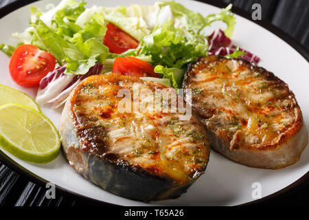 Freshly cooked sturgeon steaks served with fresh vegetable salad close-up on a plate on the table. horizontal Stock Photo