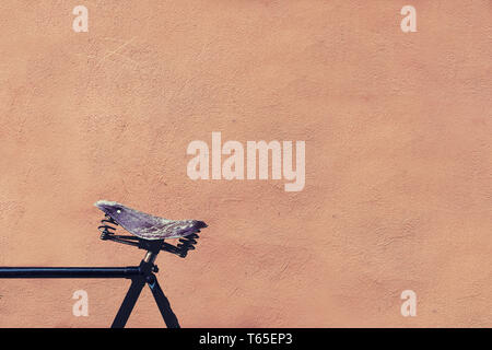 Old leather bicycle saddle against the wall Stock Photo