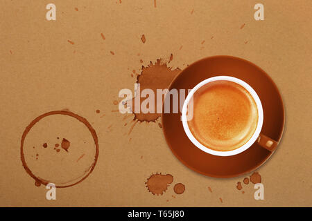 Brown cup full of espresso coffee on saucer, with ring coffee stains and drops on brown paper parchment background, elevated top view, directly above Stock Photo