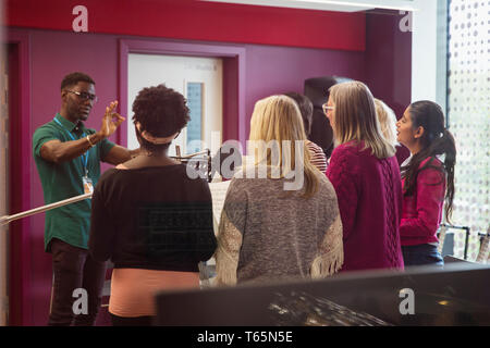 Male conductor leading women singing in music recording studio Stock Photo
