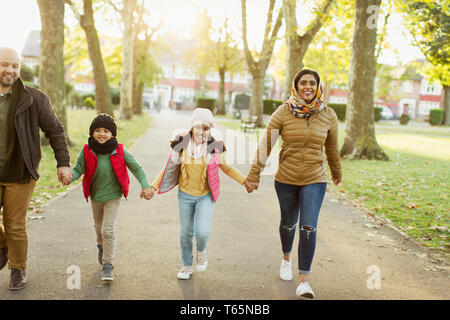 Happy Muslim family holding hands, walking in autumn park Stock Photo