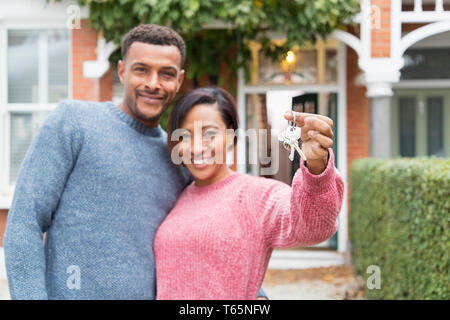 Portrait happy couple with house keys outside new house Stock Photo