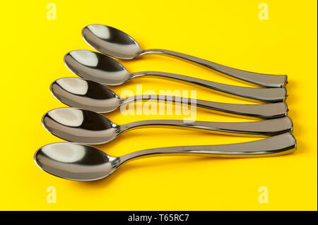plastic spoons painted under metal on a yellow background Stock Photo