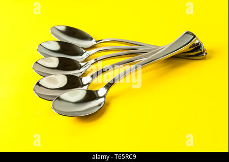 plastic spoons painted under metal on a yellow background Stock Photo