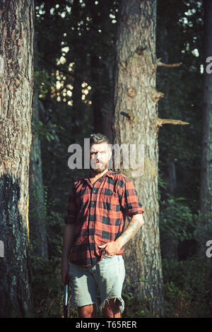 Brutal lumberjack in woods. Bearded guy holding small spade in his hands.  Young scientist doing research in wilderness. Environment and nature  concept Stock Photo - Alamy