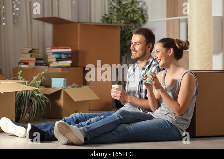 Happy couple moving home resting sitting on the floor contemplating house Stock Photo
