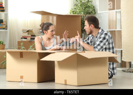 Marriage moving home fighting for a tablet sitting on the floor Stock Photo