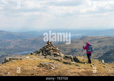 Walker Approaching the Cairn on the South Top of Tarn Crag on a Windy Day, Lake District, Cumbria, UK Stock Photo