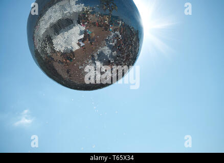 Disco balls in the sun. Giant glitter ball, with the sky as a background. Mirror disco ball. Stock Photo