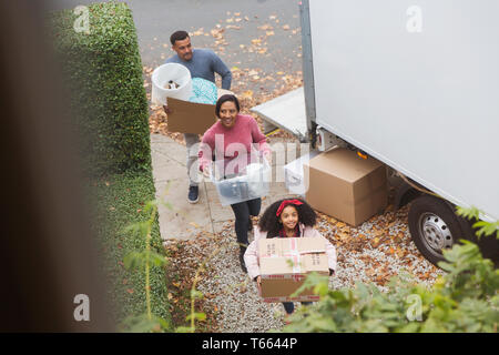 Family moving into new house, carrying boxes from moving van Stock Photo