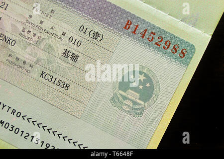China visa in passport. Close up of national emblem and elements of official document issued by Chinese Embassy with inscriptions. Inclined front view Stock Photo