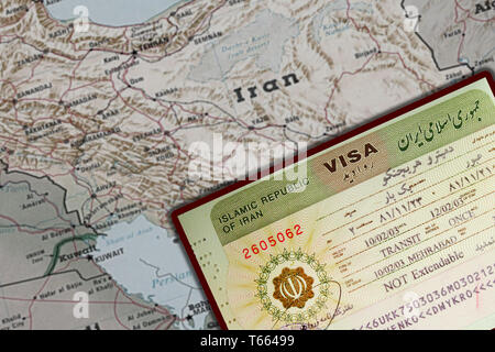 Iran visa in passport. Close up of official document issued by I.R.I. Embassy with national emblem. Blurred Iranian map on background Stock Photo