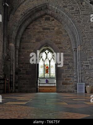 A view of a stained glass window through an arched medieval doorway, in St David's Cathedral, Pembrokeshire, West Wales Stock Photo