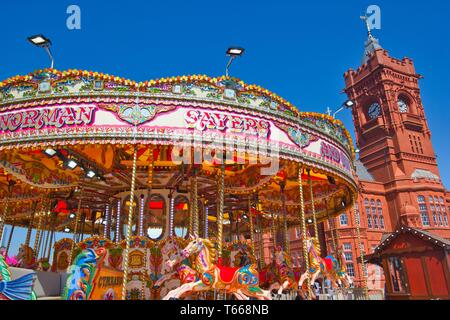 Fairground carousel ride and tower of the Grade 1 Listed Pierhead Building (Adeilad y Pierhead), Cardiff Bay, Wales, United Kingdom.