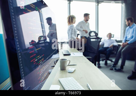 Close-up of workplace in modern office with business people behind. Colleagues meeting to discuss their future financial plans. Stock Photo