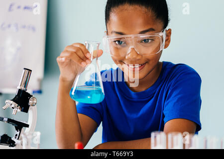 Young African American kid test chemistry lab experiment and shake glass tube flask with microscope and smile - science and learning education concept Stock Photo