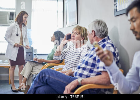 Doctor and patients in clinic waiting room Stock Photo