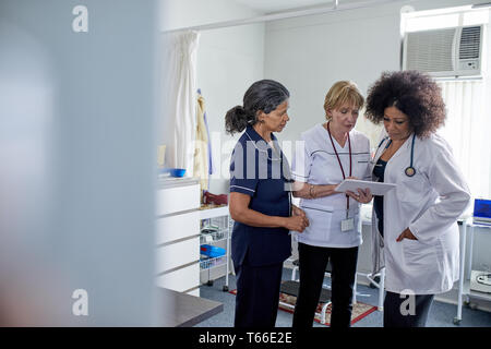 Female doctor and nurses using digital tablet in clinic examination room Stock Photo