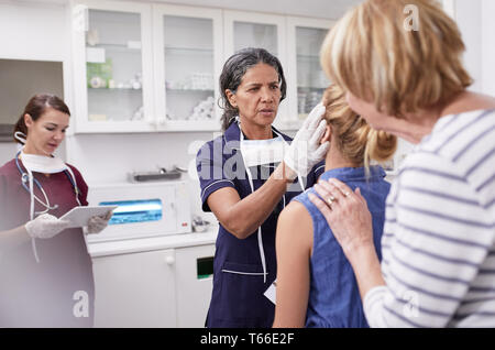 Female pediatrician examining girl patient in clinic examination room Stock Photo