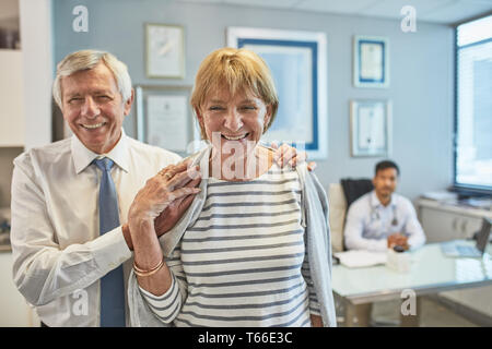 Portrait happy senior couple leaving clinic doctors office Stock Photo