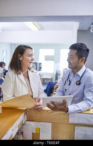 Doctors with digital tablet and medical record talking in clinic Stock Photo