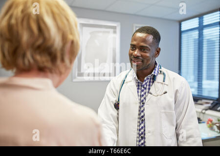 Male doctor talking to senior female patient in doctors office Stock Photo