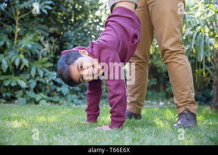 Portrait playful boy hanging upside down in backyard Stock Photo