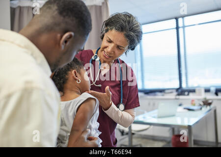 Female pediatrician examining girl patient in clinic examination room Stock Photo